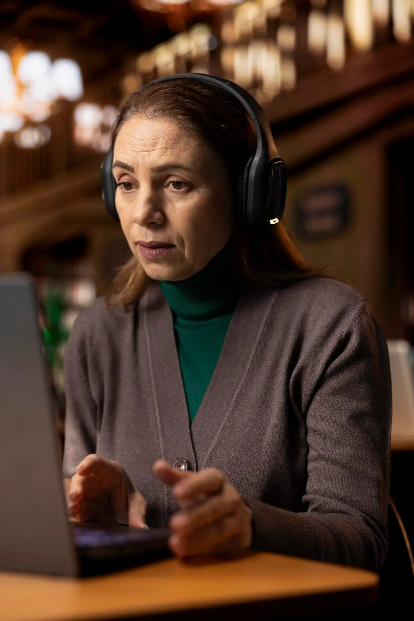 Зрелая женщина сидит в библиотеке кампуса на видеозвонке для семинара.